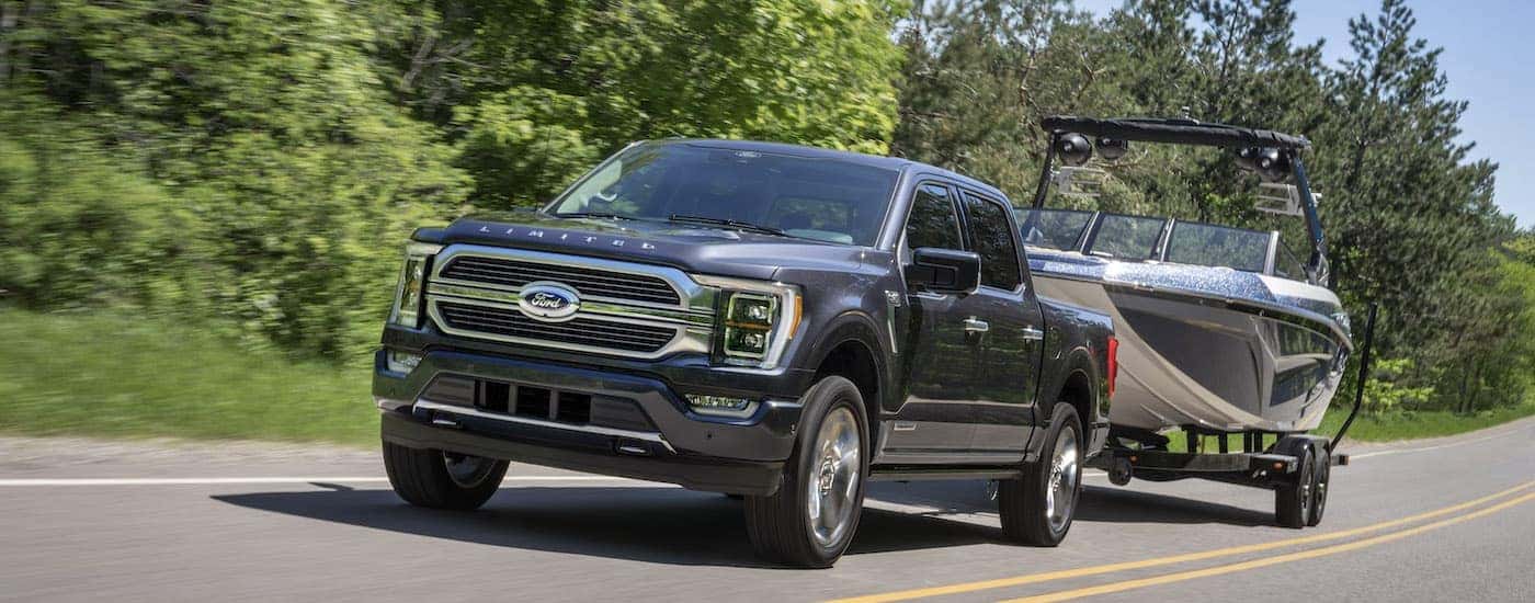 A grey 2022 Ford F-150 Limited is shown from the front while towing a boat.