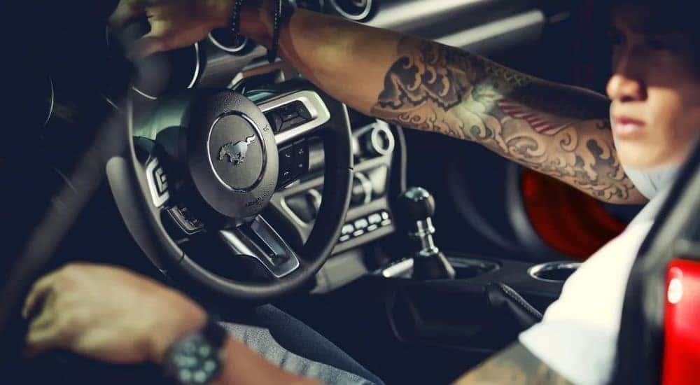 A person is shown inside a red 2022 Ford Mustang.