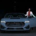 A person is shown exiting a pale blue 2024 Ford Mustang in a tunnel.