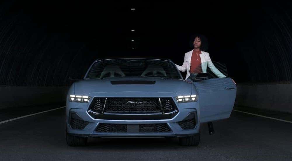 A person is shown exiting a pale blue 2024 Ford Mustang in a tunnel.