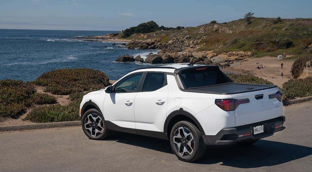 A white 2022 Hyundai Santa Cruz is shown parked near an ocean.