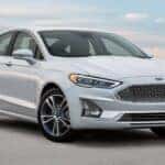 A white 2020 Ford Fusion is shown parked at a used car dealer near Indianapolis.