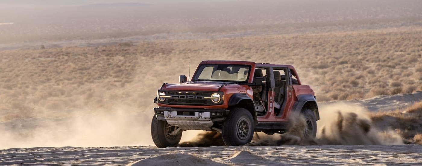 A red 2022 Ford Bronco Raptor is shown from the front at an angle while off-road.