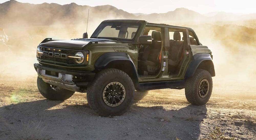 A green 2024 Ford Bronco is shown driving off-road in a desert.