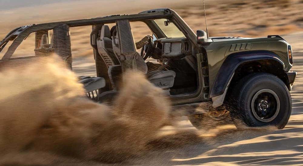 A green 2024 Ford Bronco is shown from the side driving off-road through a desert.