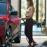 A person is shown charging a red 2024 Ford Mustang Mach-E for sale.