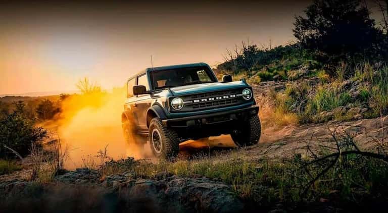 A green 2024 Ford Bronco is shown driving off-road