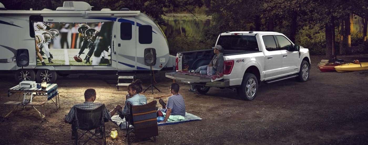 A white 2024 Ford F-150 is shown parked on a camp-site.