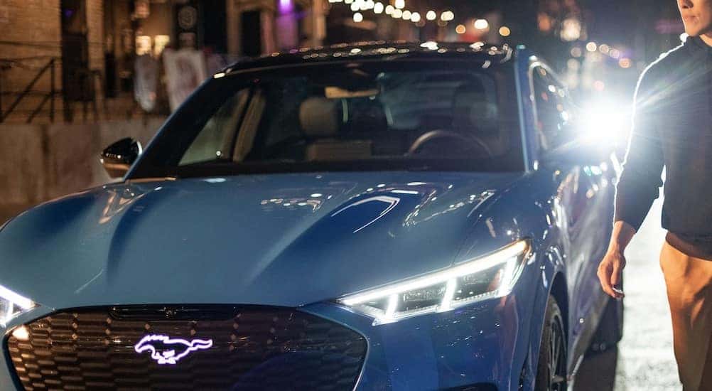 A blue 2024 Ford Mustang Mach-E is shown parked near a person.