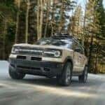 A tan 2024 Ford Bronco Sport Badlands is shown driving off-road after visiting a car dealership near Indianapolis.