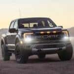 A gray 2024 Ford F-150 Raptor is shown parked with the headlights on agter visiting a Ford truck dealer.