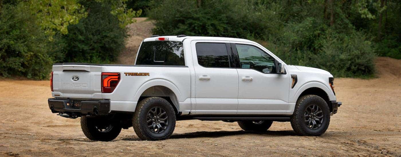 A white 2024 Ford F-150 Tremor is shown from the side while off-road.