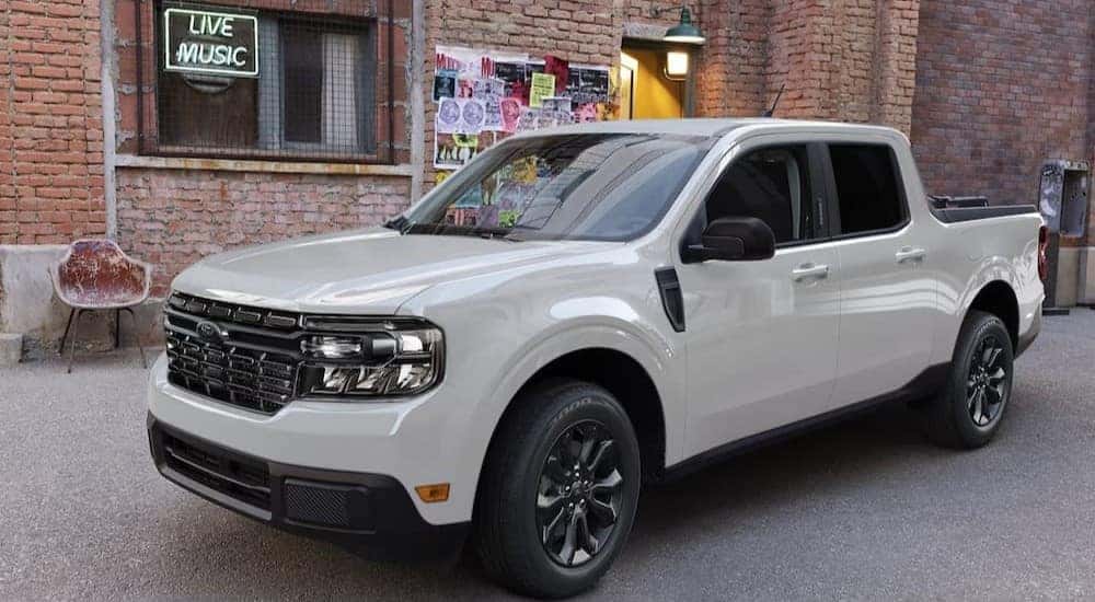 A white 2024 Ford Maverick is shown parked near a brick building.