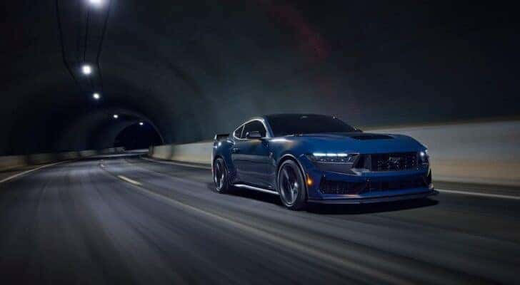 A blue 2024 Ford Mustang Dark Horse is shown from the front at an angle after leaving a Ford dealer near Speedway.