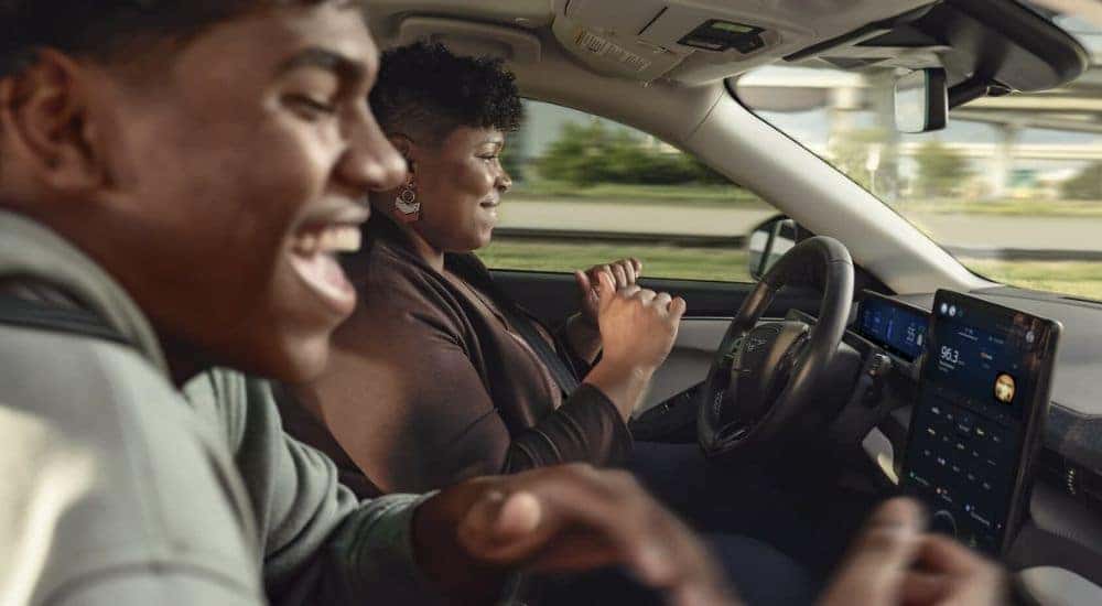 Smiling people are shown riding in a 2022 Ford Mustang Mach-E.