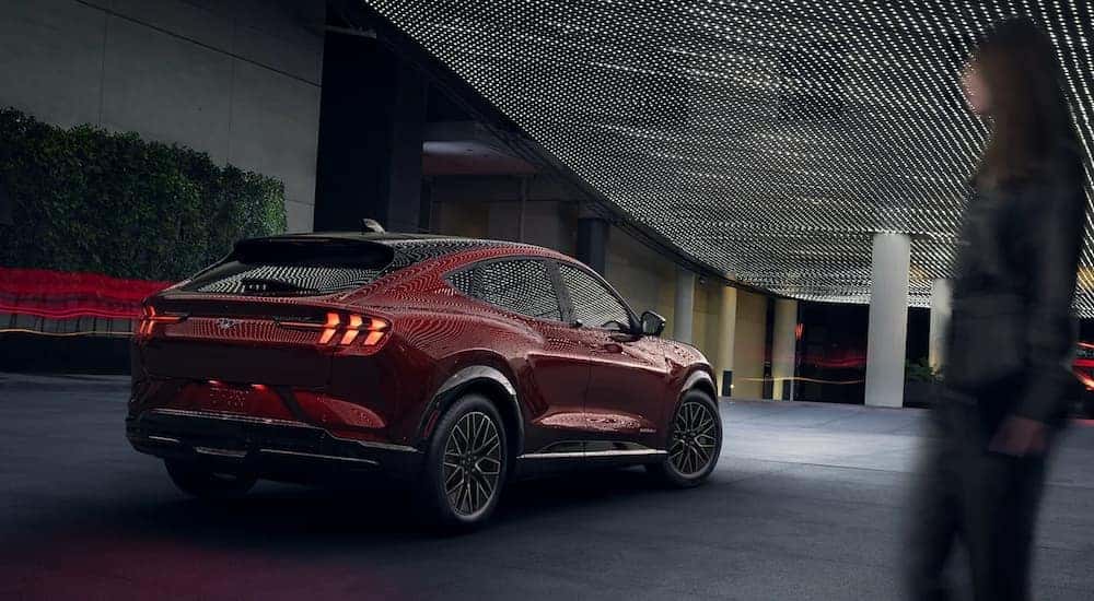A red 2024 Ford Mustang Mach-E driving in a city.