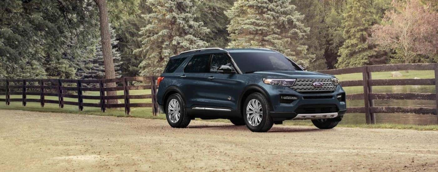 A dark green 2023 Ford Explorer King Ranch driving by a fence.