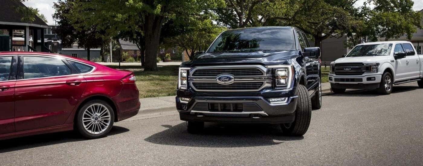 A black 2023 Ford F-150 pulling out of a parking spot by a curb.