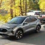 A silver 2024 Ford Escape is shown towing a boat to a Ford dealer near Avon.