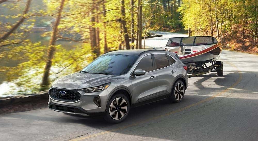 A silver 2024 Ford Escape is shown towing a boat to a Ford dealer near Avon.