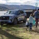 A blue 2025 Ford Explorer is parked near a campsite next to a lake.