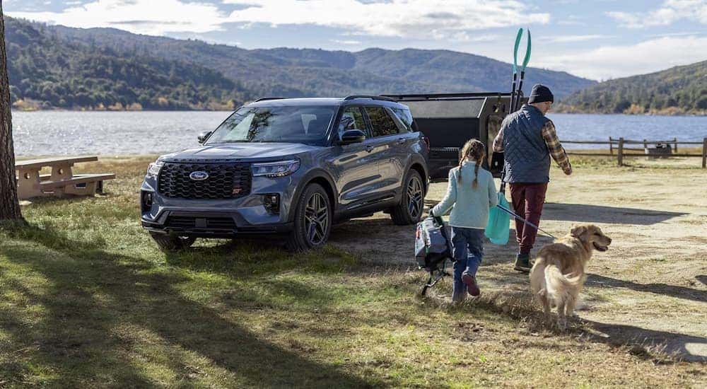 A blue 2025 Ford Explorer is parked near a campsite next to a lake.