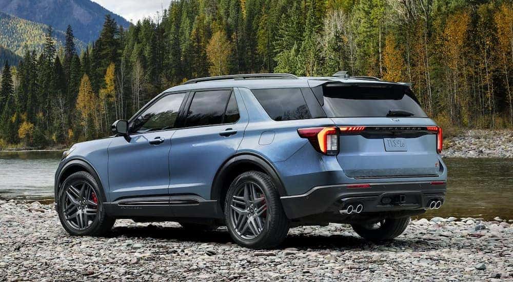 A blue 2025 Ford Explorer ST is parked on rocks next to a river.