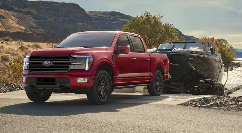 A red 2024 Ford F-150 is shown towing a boat.