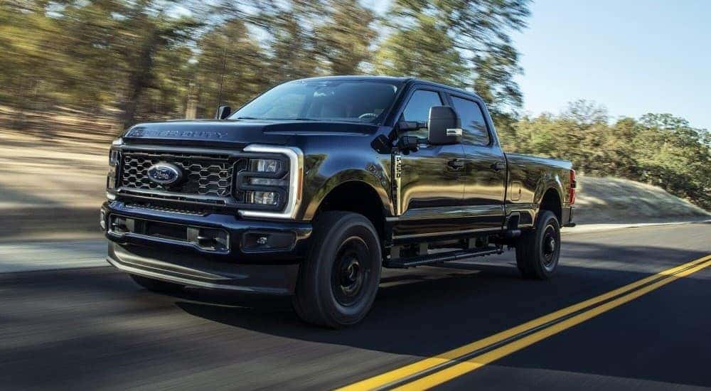 A black 2023 Ford F-250 XL is shown driving on a highway after viewing trucks for sale.
