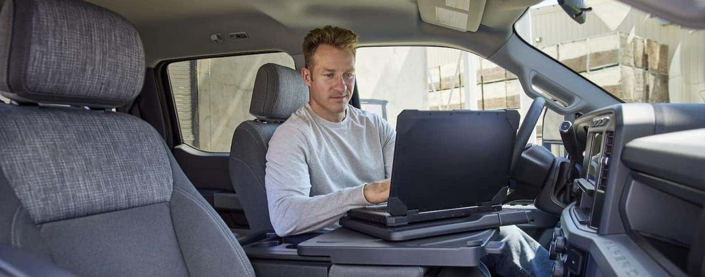 A person is shown using a laptop in a 2024 Ford F-350.