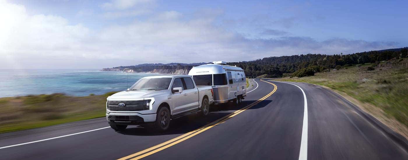 A white 2025 Ford F-150 Lightning is shown from the front at an angle.