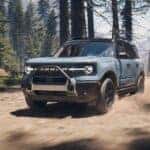 A blue 2025 Ford Bronco Sport Outer Banks is shown driving in a forest.