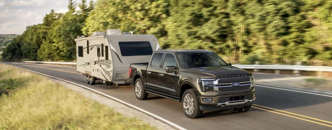 A gray 2025 Ford F-150 Platinum towing a trailer.