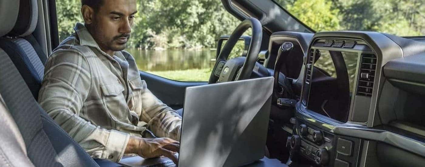 A person using a laptop in a 2025 Ford F-150.