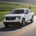 A white 2025 Ford Maverick for sale driving on a highway.