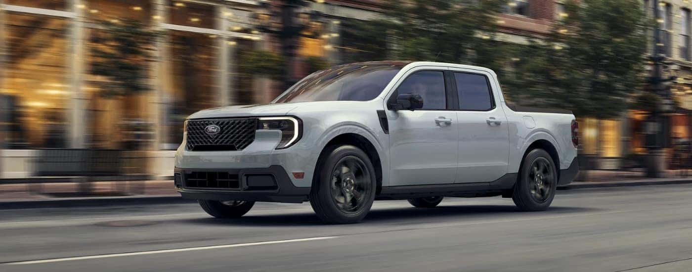 A white 2025 Ford Maverick driving down a city street