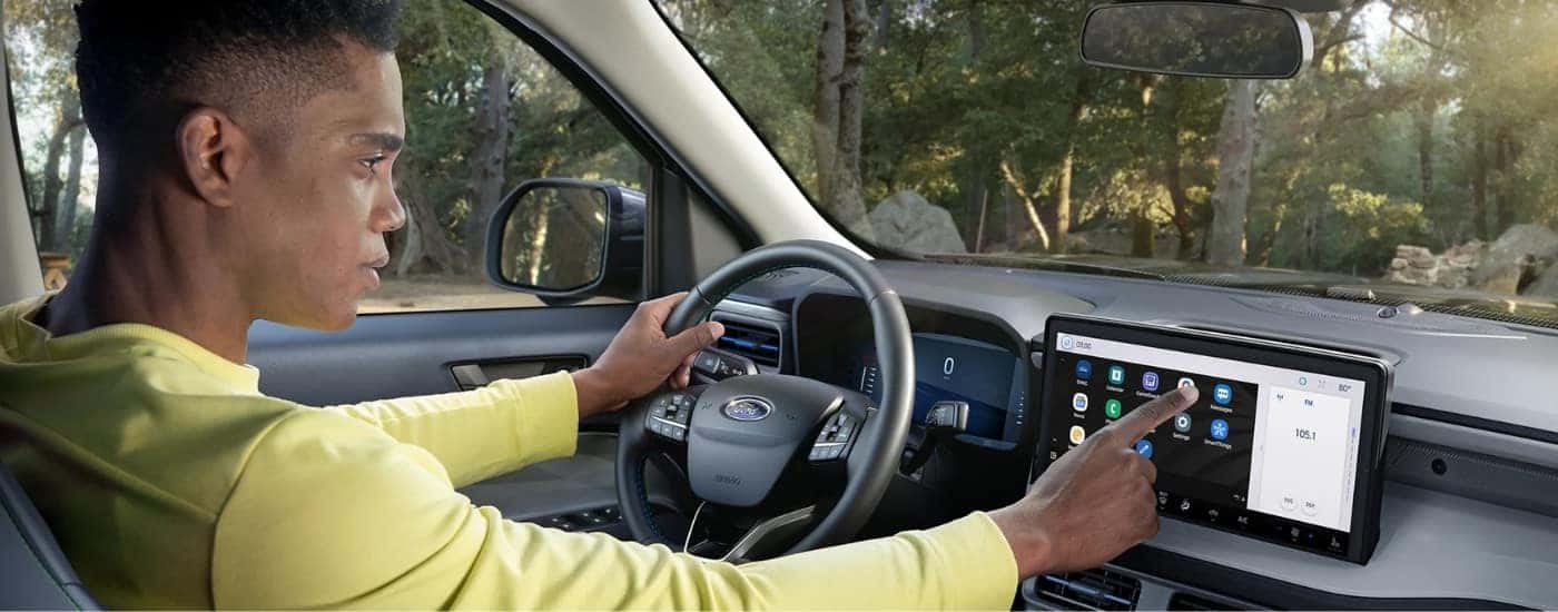 A man using the infotainment touchscreen on a Ford Maverick for sale near Indianapolis