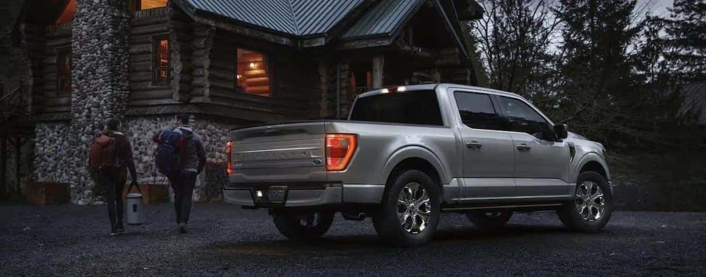 A silver 2021 Ford F-150 Platinum parked near a log cabin.
