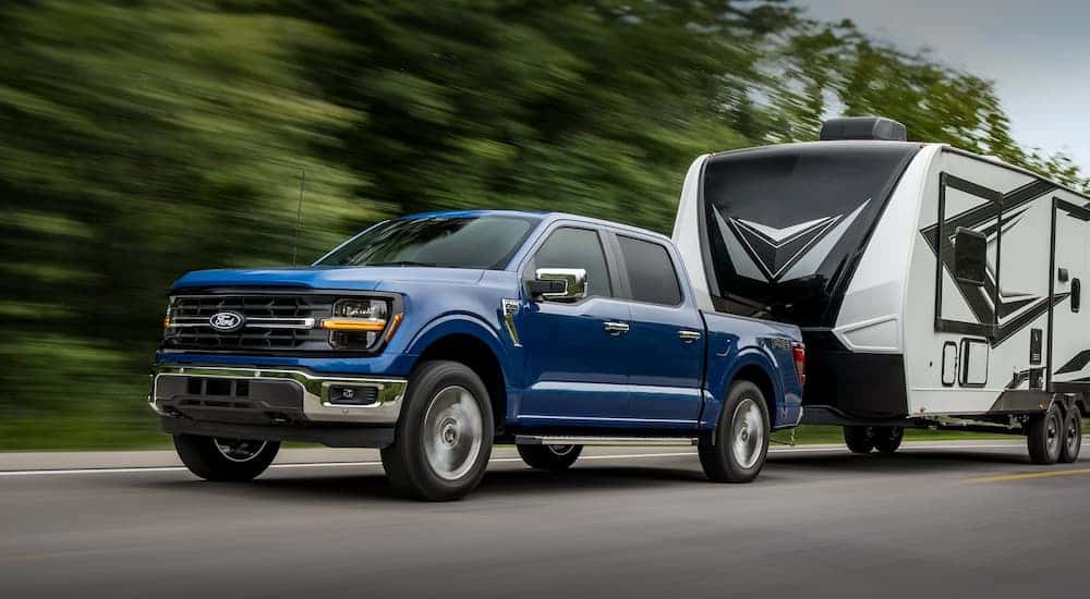 A blue 2025 Ford F-150 towing a camper behind