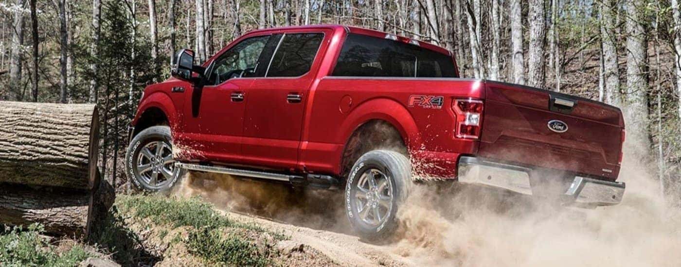 A red 2018 Ford F-150 XLT kicking up dust off-road.