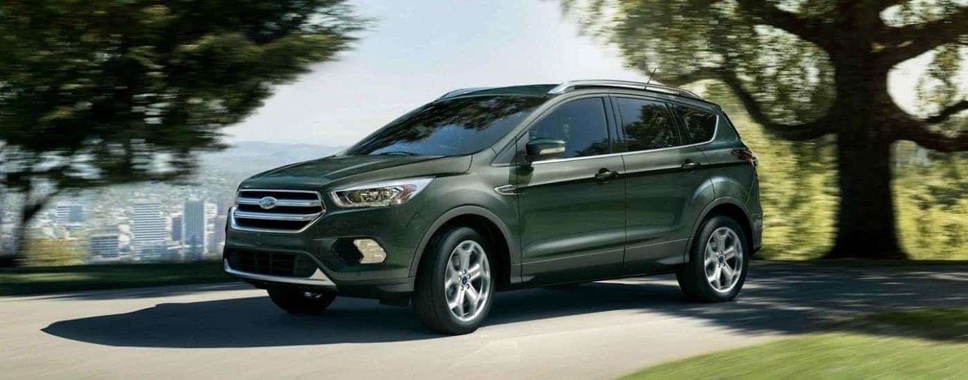 A green 2019 Ford Escape driving past a distant city.