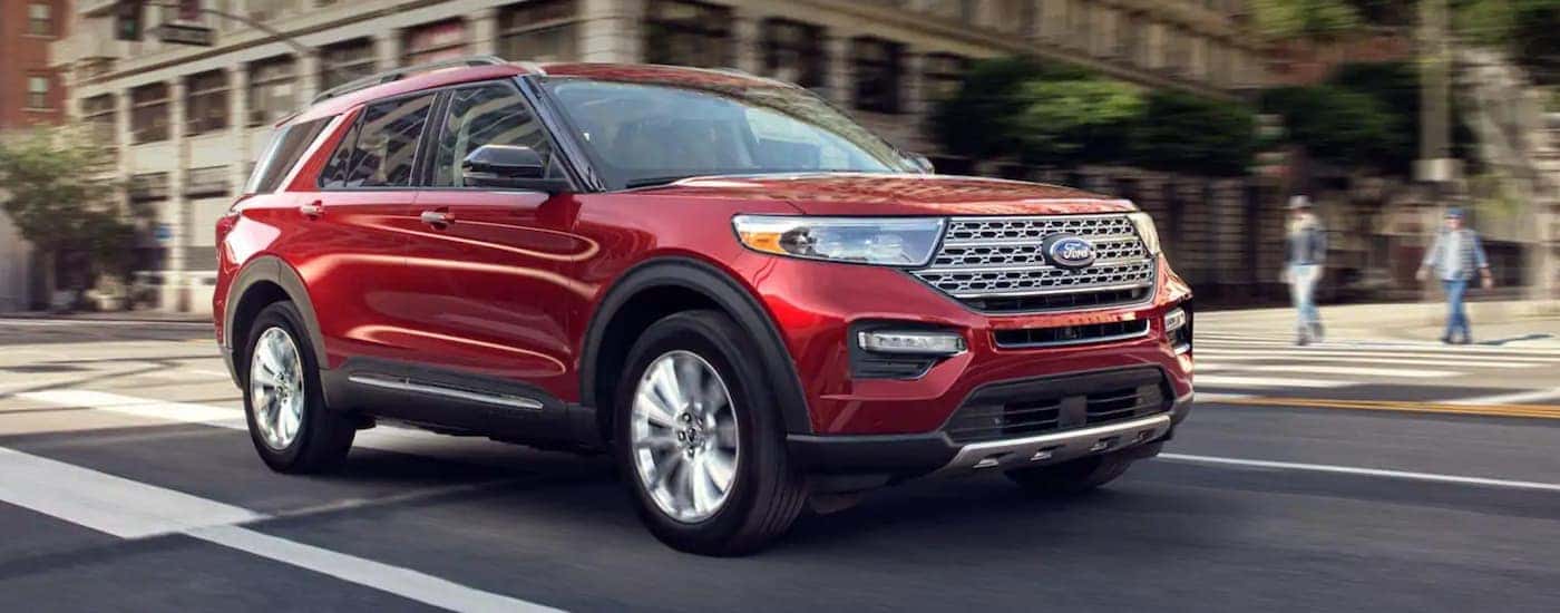 A red 2020 Ford Explorer driving through a city to a used Ford dealer.