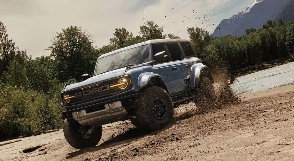 A blue 2025 Ford Bronco Raptor kicking up mud