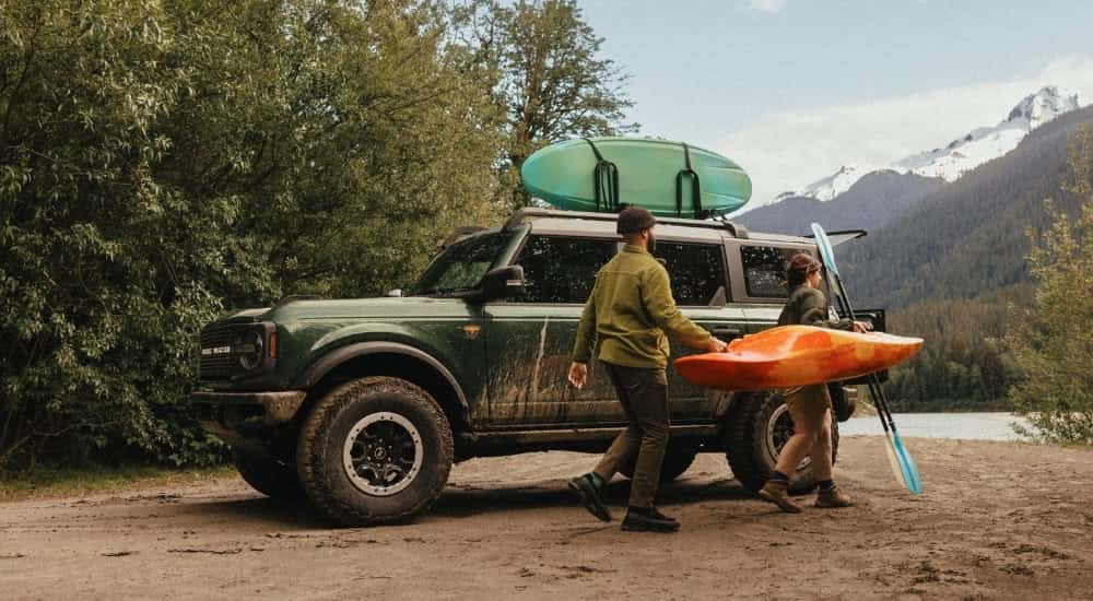 People carrying a kayak near a green 2025 Ford Bronco for sale near Indianapolis