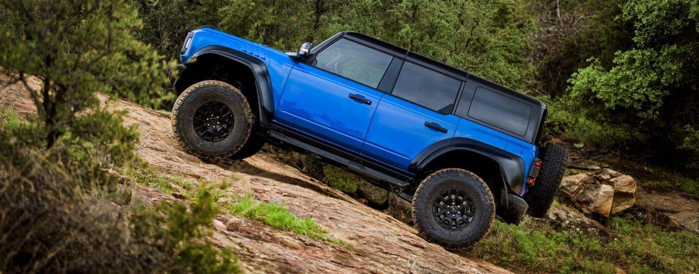 A blue 2025 Ford Bronco Raptor off-roading on a trail