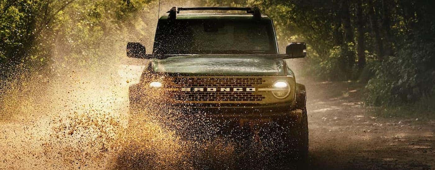 A green 2025 Ford Bronco off-roading in mud
