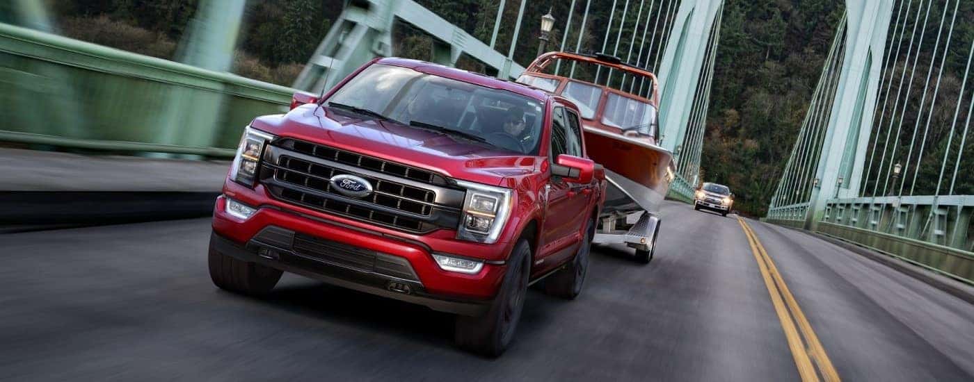 Red 2021 Ford F-150 towing a boat over a bridge