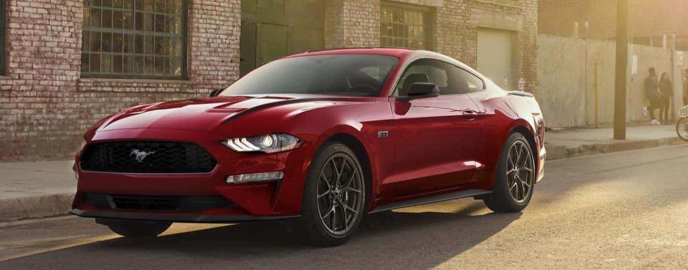 A red 2022 Ford Mustang is shown in front of a brick building after leaving a used car dealer near Fishers.