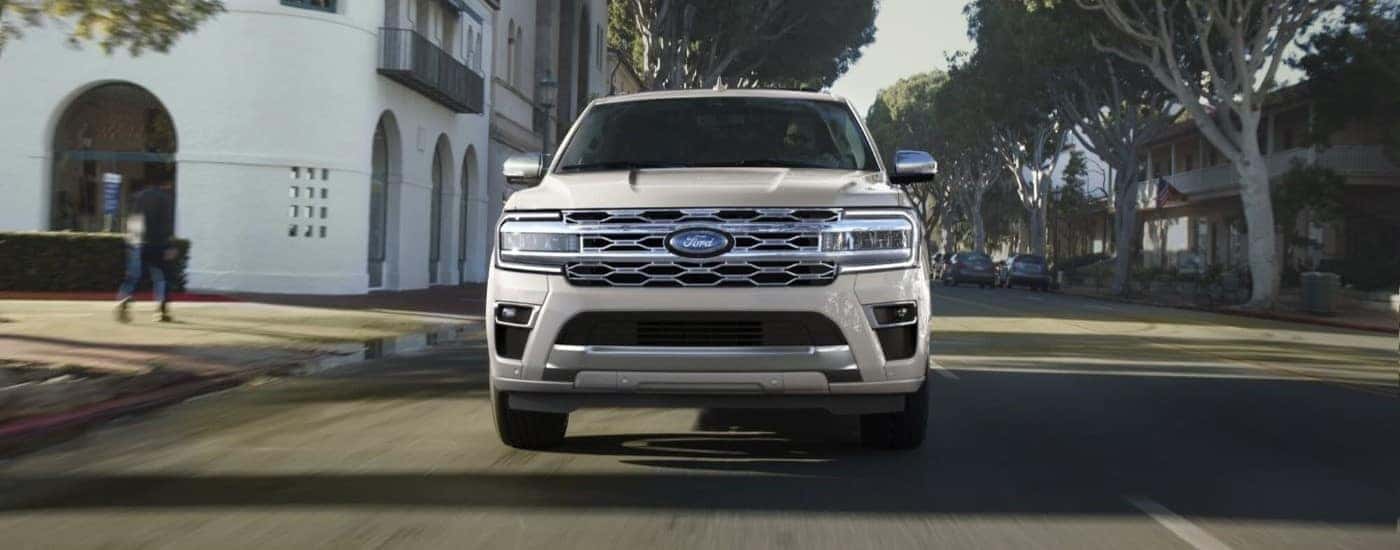 A white 2023 Ford Expedition is shown from the front driving on a city street.