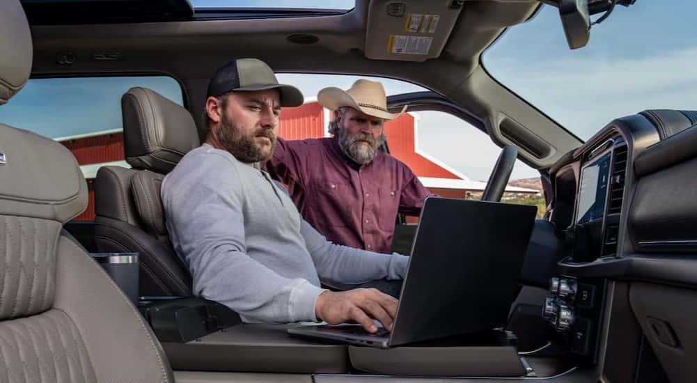 Two people using a laptop in a 2026 Ford F-150 for sale in Zionsville.